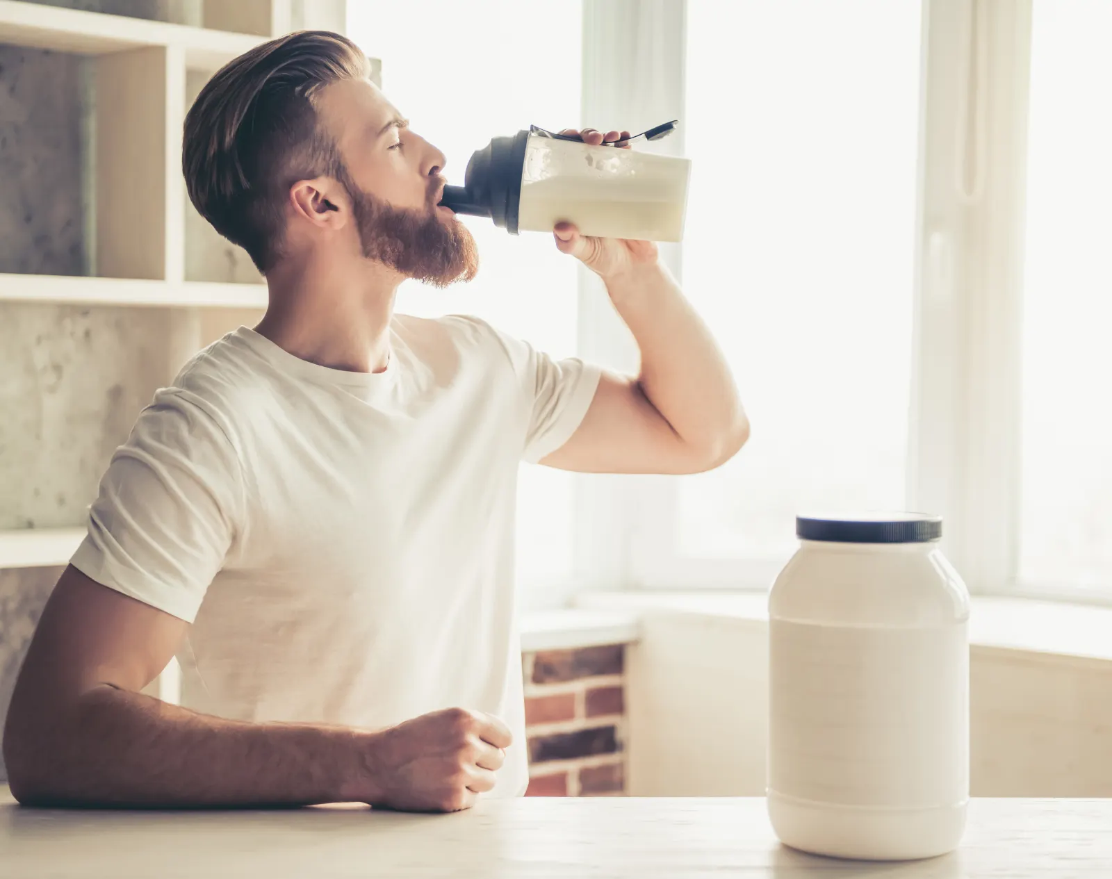 Homme qui boit un shake protéiné dans sa cuisine